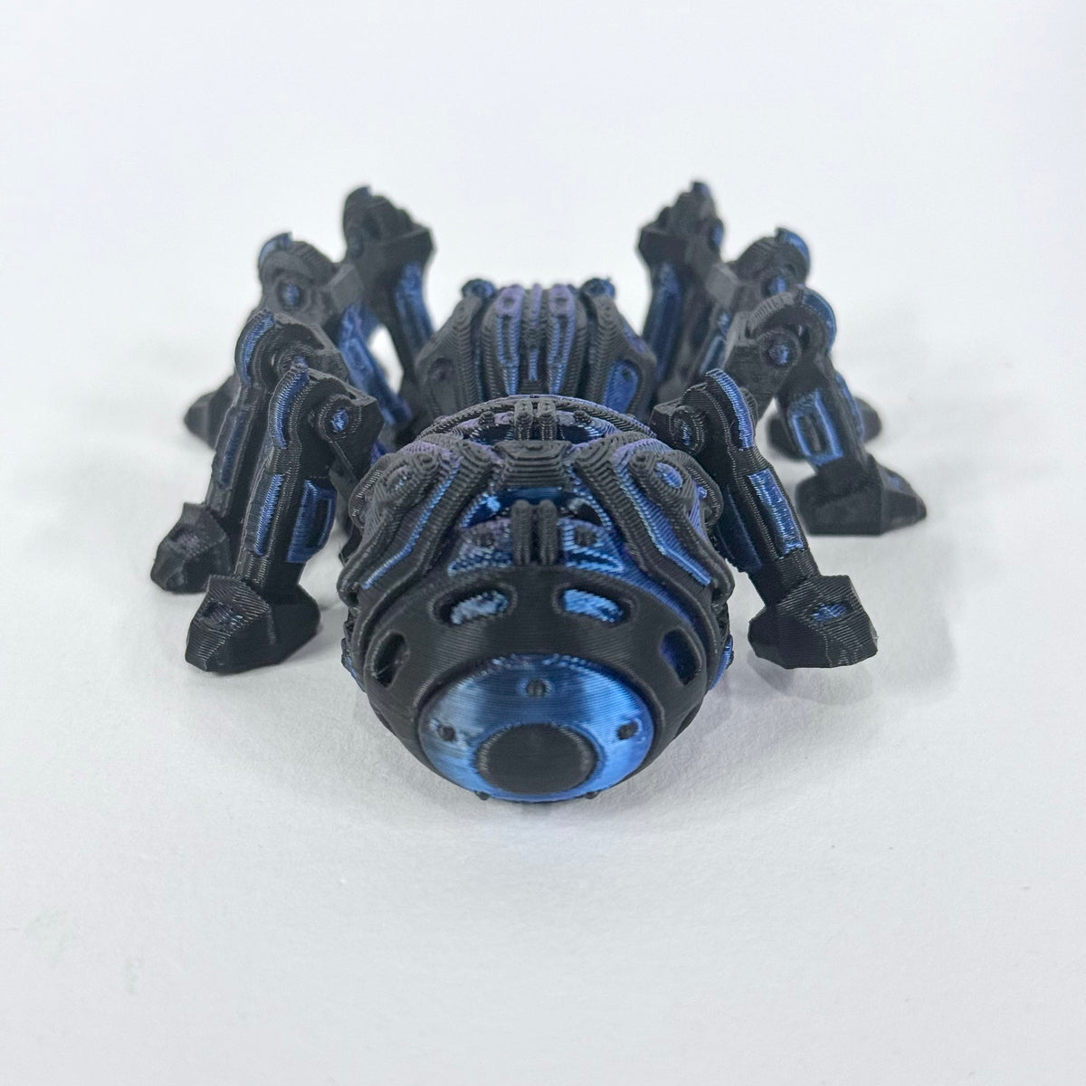 Cyber Spider photographed from above, showing the articulated leg layout and contrasting blue and purple accents on the black body.
