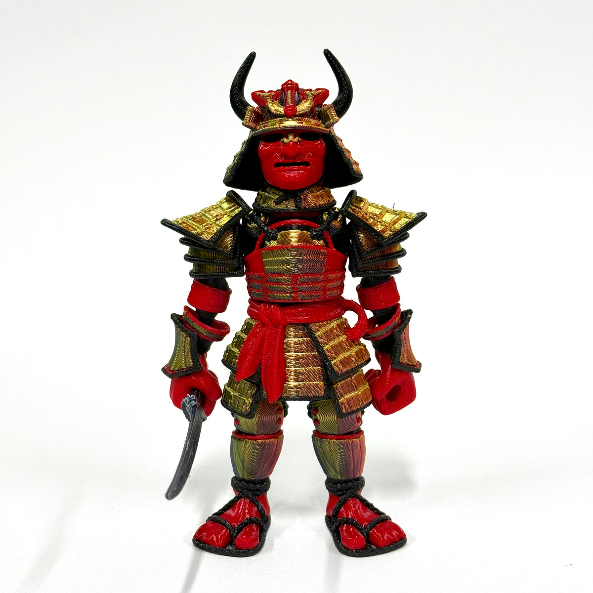 A red and gold samurai warrior action figure standing on a white background, holding a curved sword.